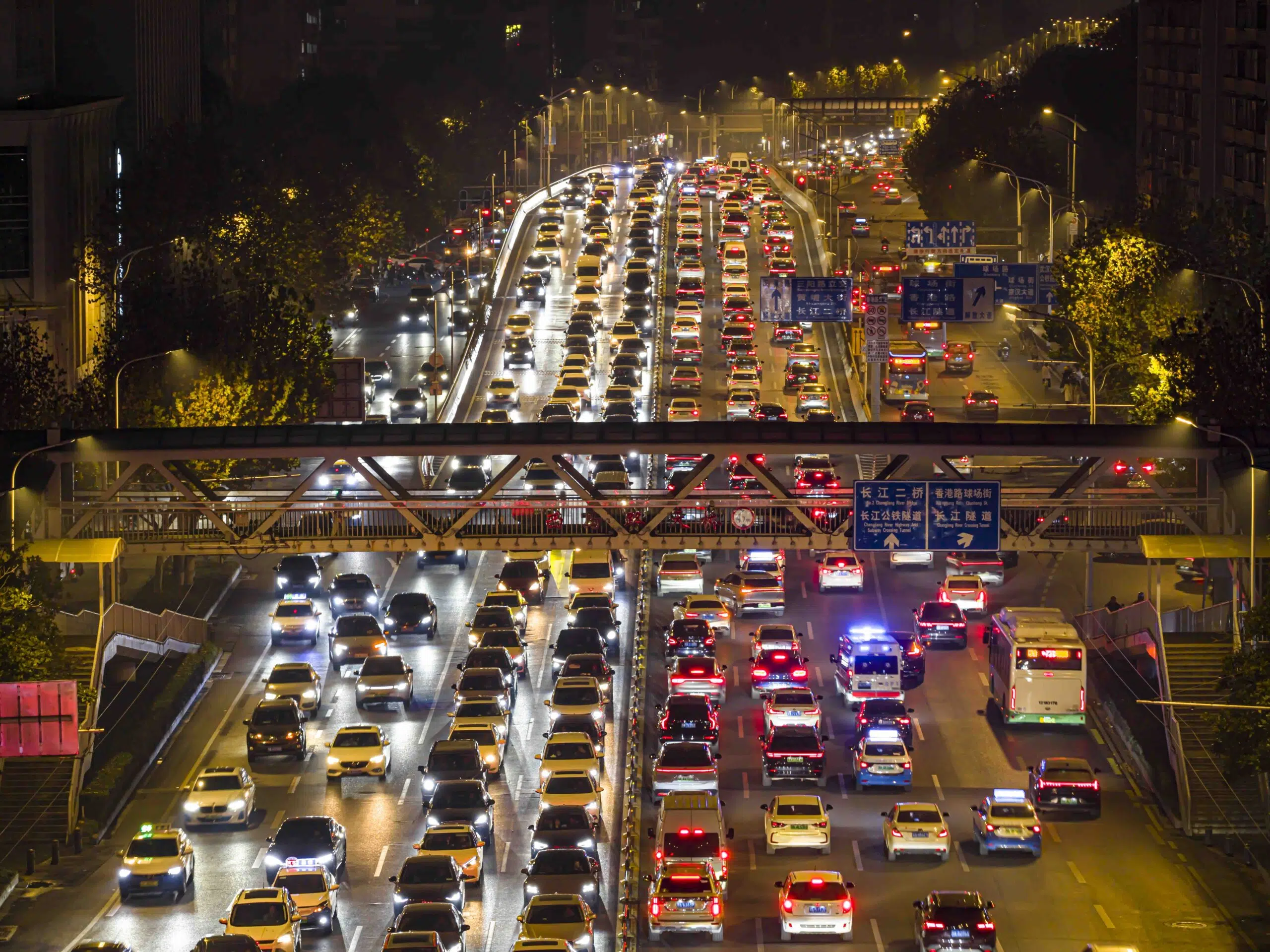 Wuhan, China - Dec 17, 2025: Aerial night view of heavy traffic congestion during evening rush hour. Thousands of cars with glowing headlights and taillights jam the urban highway and overpass in a dense city flow.